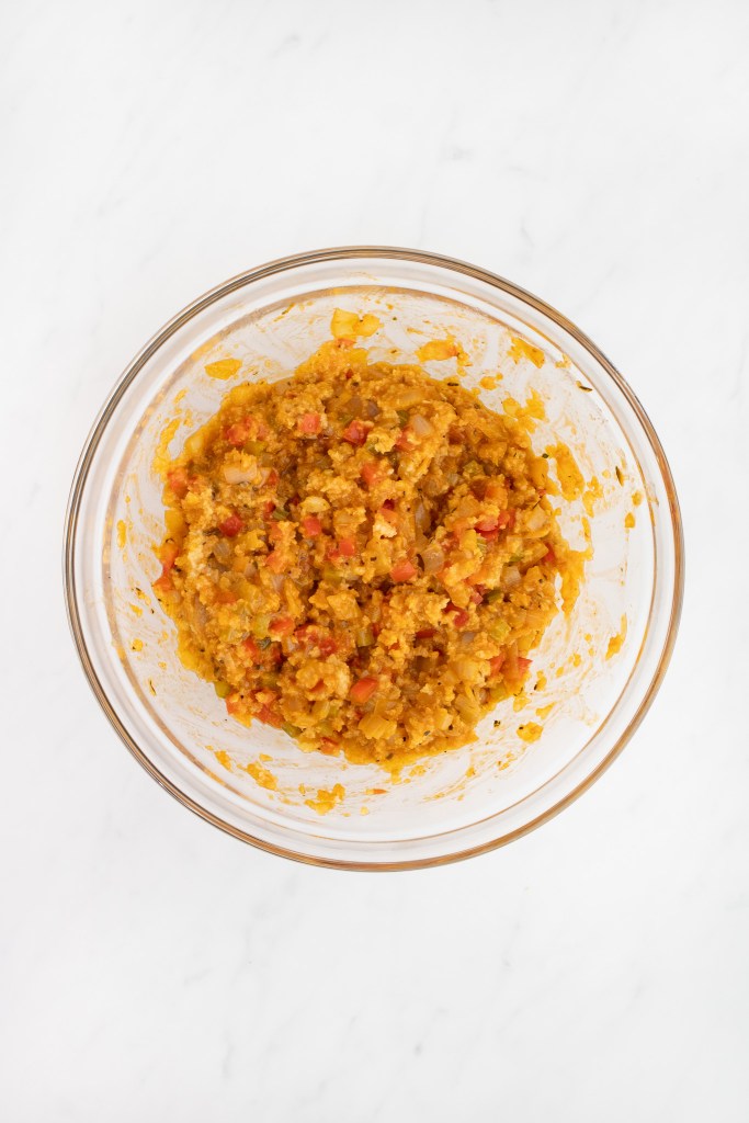 A glass bowl filled with panko mixture combined with vegetable mixture sits on a white marble surface.