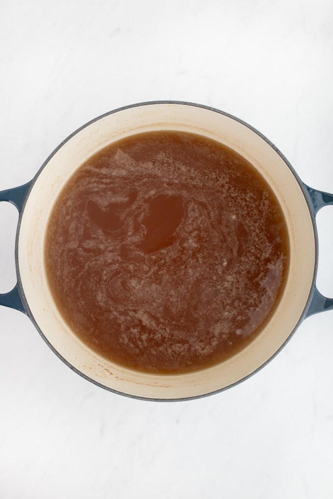 A round cast iron pot filled with brown boiling liquid.